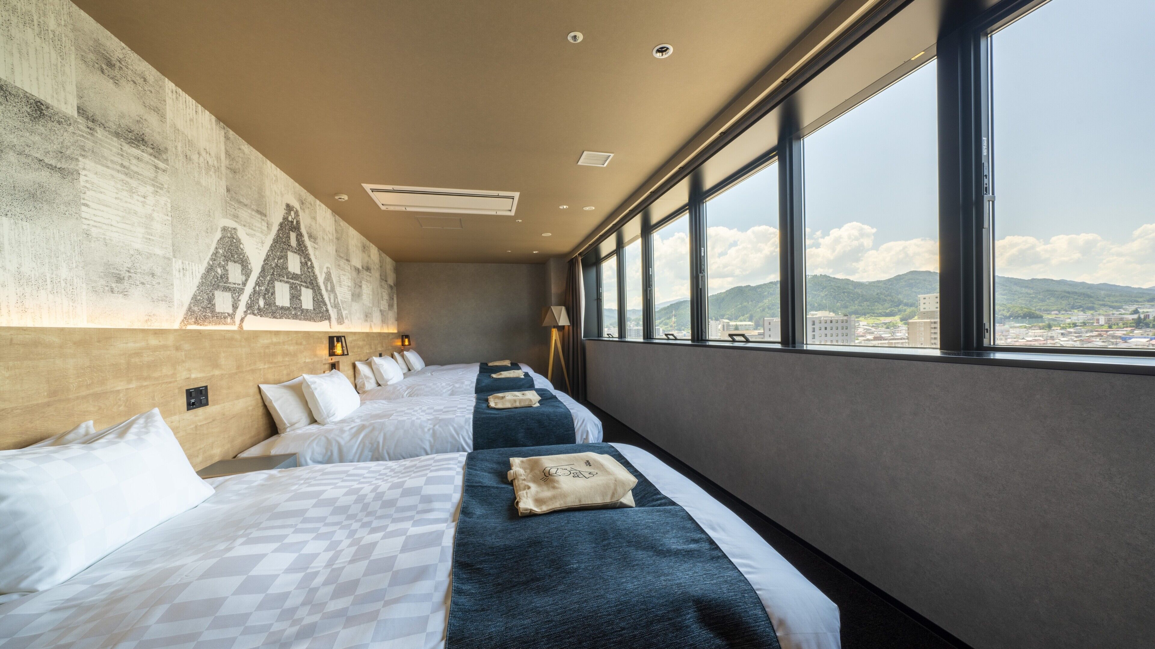 Une chambre d’hôtel avec un grand lit, un lit plus petit, une vue sur la ville et une fresque murale.