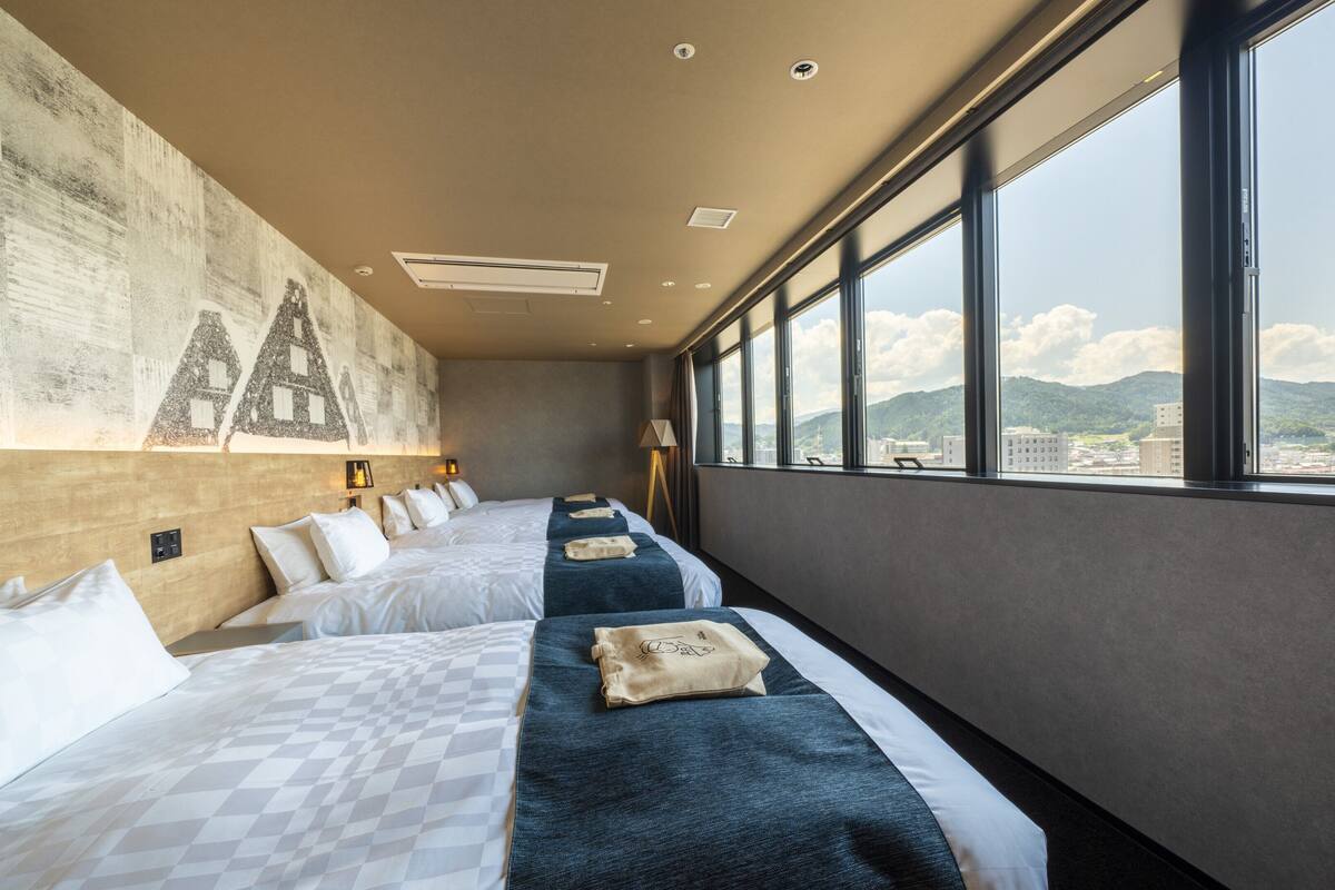 A hotel room with a large bed, a smaller bed, a view of the city, and a mural on the wall.