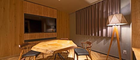 Un comedor moderno con una mesa y sillas de madera, un televisor de pantalla plana y una lámpara.