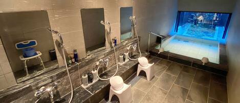 Un baño moderno con un tocador amplio, varios lavamanos, un espejo grande y una bañera con vistas a un acuario.