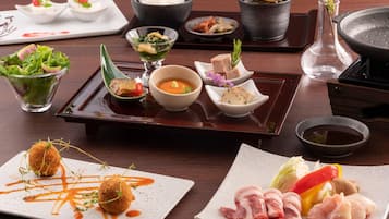 A variety of dishes on a wooden table, including a salad, soup, and meat.