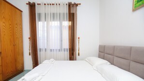 Une chambre d’hôtel avec un lit, une armoire en bois et une fenêtre avec des rideaux.