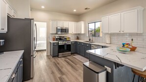 A modern kitchen with white cabinets, stainless steel appliances, and a marble countertop. - The Desert Hideaway | Game Room, Pool & Outdoor Kitchen [Free Spa Heating + Early Check-In] (Indio)
