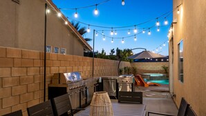 An outdoor patio with a grill, seating, and a pool. - The Desert Hideaway | Game Room, Pool & Outdoor Kitchen [Free Spa Heating + Early Check-In] (Indio)