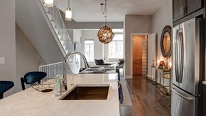 A modern kitchen with a marble countertop, stainless steel appliances, and a wooden staircase. - South Slope Skyhaus with Rooftop Terrace (Asheville)