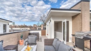 A rooftop patio with outdoor furniture, a grill, and a view of the city skyline. - South Slope Skyhaus with Rooftop Terrace (Asheville)