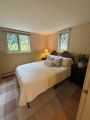 A bedroom with a bed, two bedside tables, a lamp, and a window. - Serene mountain escape with beautiful views and a hot tub (Jefferson)