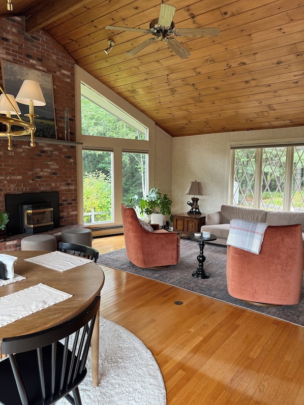 A cozy living room with a fireplace, wooden ceiling, and large windows. - Serene mountain escape with beautiful views and a hot tub (Jefferson)