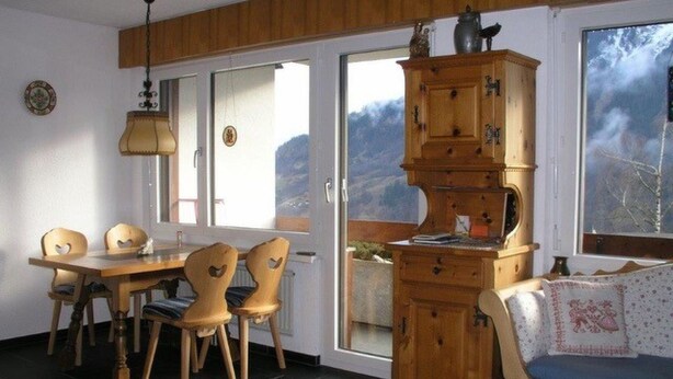 Un coin repas accueillant avec une table et des chaises en bois, un meuble avec de nombreux tiroirs et une fenêtre donnant sur l’extérieur.