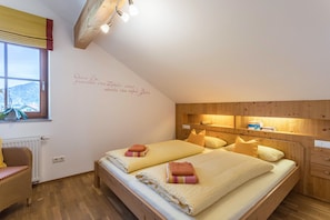 Une chambre avec deux lits, des têtes de lit en bois, une fenêtre avec vue et un mur orné d’une citation.