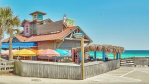 En byggnad vid stranden med ett halmtak, färgglada parasoller och en skylt som annonserar för ”Margaritaville”.