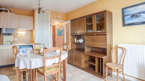 Une cuisine de taille réduite avec des meubles de rangement en bois, une table à manger avec des chaises et un radiateur blanc.