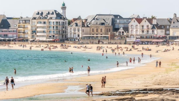 Une plage avec une rangée de bâtiments en arrière-plan.