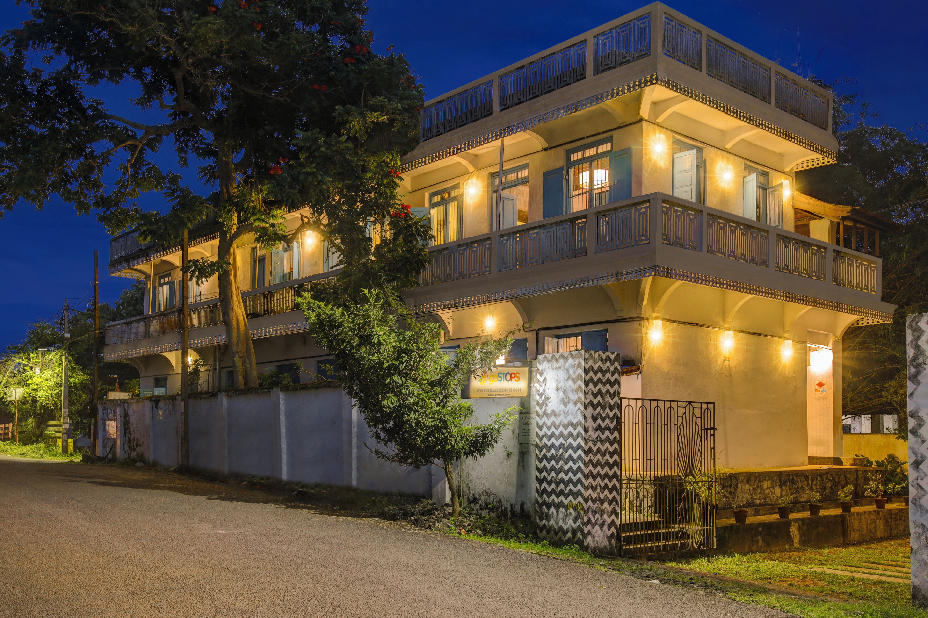 A multi-story hotel with balconies, a gated entrance, and a well-lit facade.