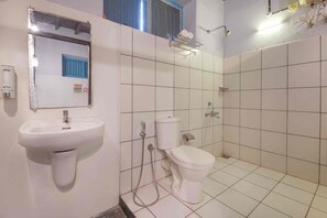 A bathroom with a white sink, toilet, and shower. There is a mirror above the sink and a towel rack on the wall.