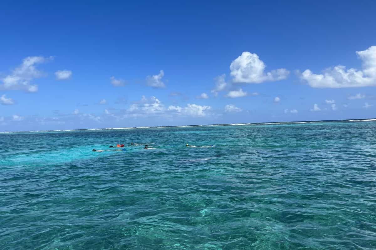 Ein klares, blaues Meer, in dem einige Personen schwimmen.