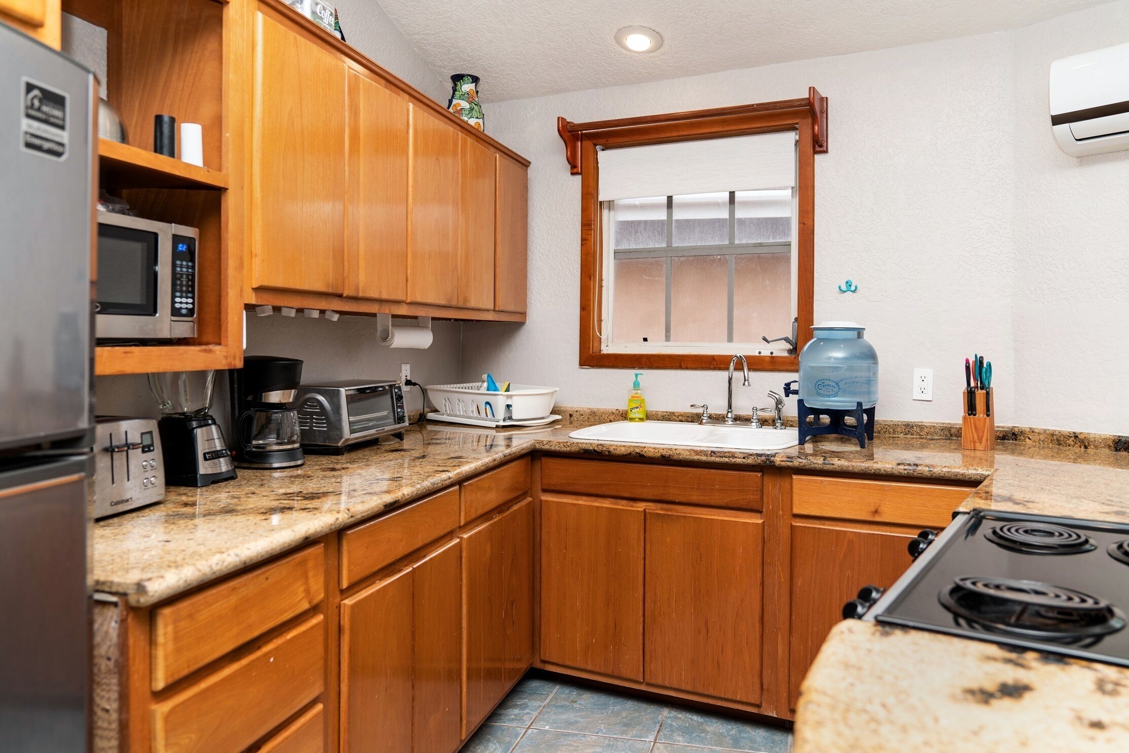 A kitchen with wooden cabinets, a microwave, a coffee maker, a toaster, and a sink.