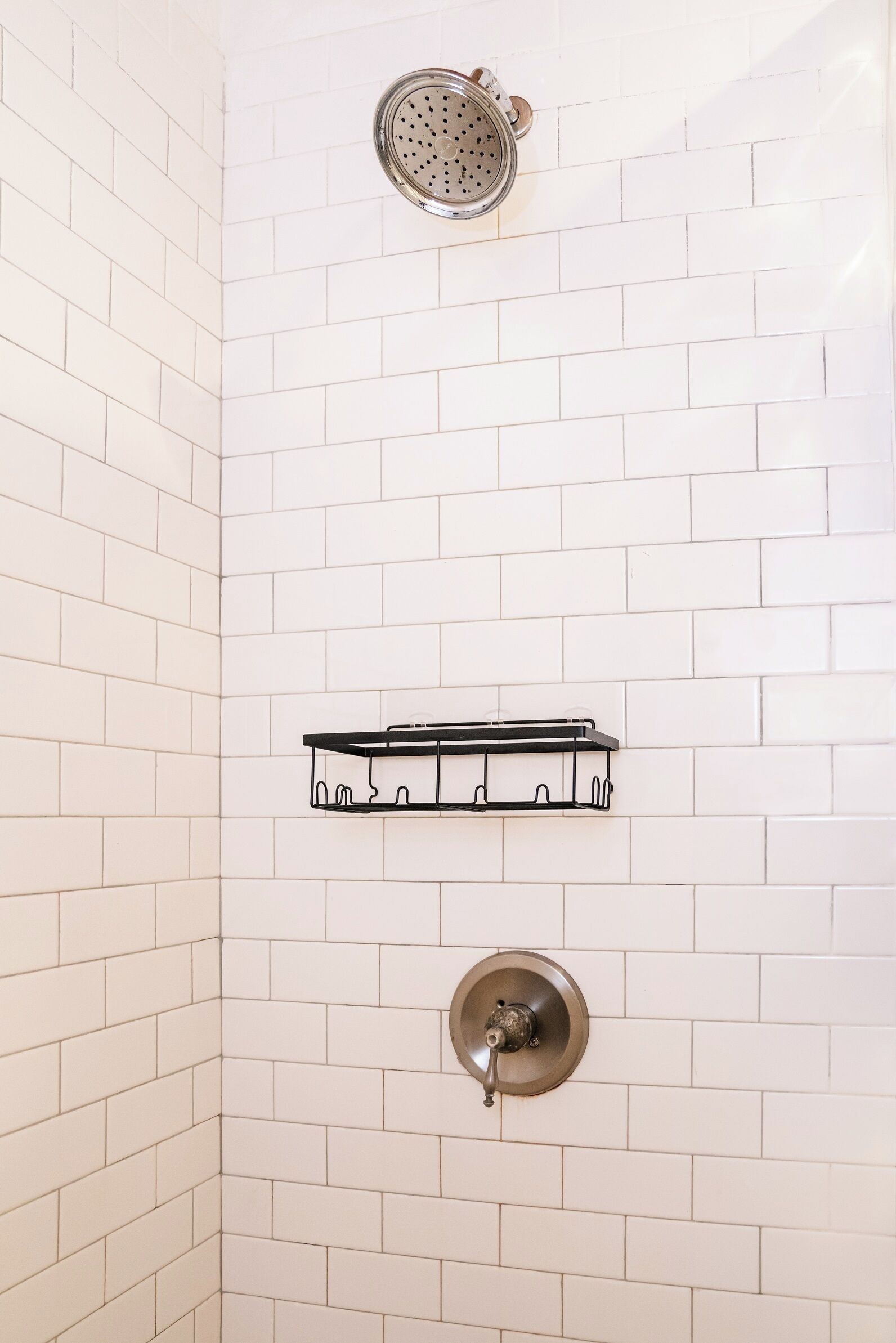 A shower with a round showerhead and a wall-mounted towel rack.
