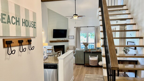 A modern kitchen with a built-in dishwasher, a dining area with a table and chairs, and a staircase with wooden railings. - Flash Sale Completely updated 3/2 Sleeps 8 ML1 (Orange Beach)