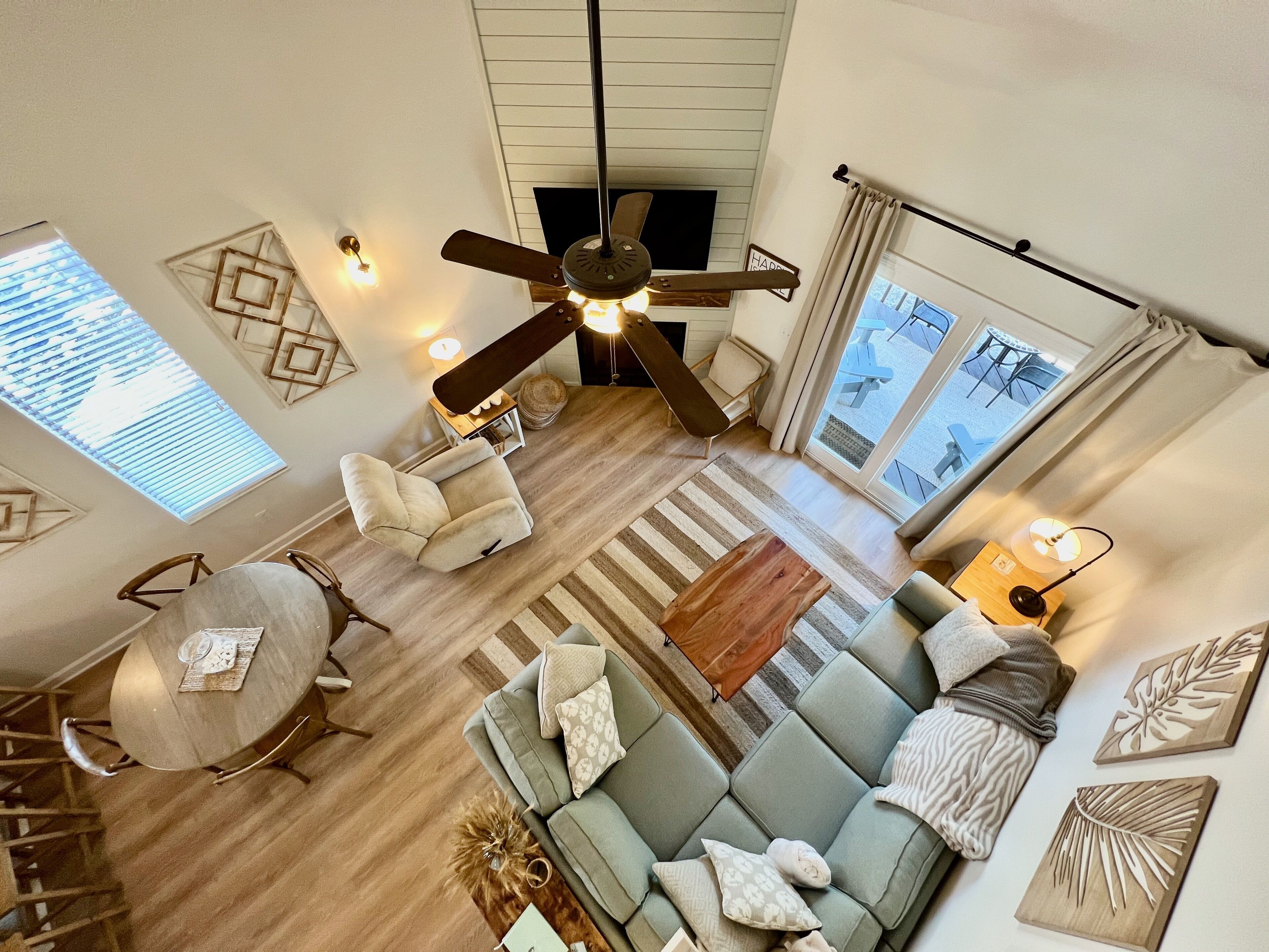 Un salon spacieux doté d’un ventilateur de plafond, d’un canapé, d’une table basse et d’un coin repas avec une table ronde et des chaises.