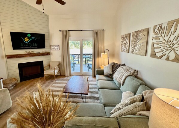 A living room with a fireplace, sofa, and a television displaying 'Island Retreat'.