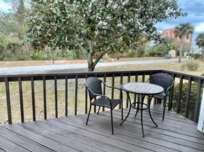 A wooden deck with two wicker chairs and a small round table.