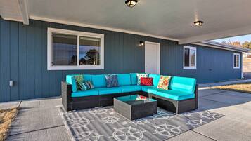 A covered outdoor seating area with a sectional sofa and a coffee table.