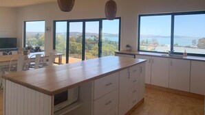 Una cocina moderna con ventanas amplias, un comedor y vista al mar.
