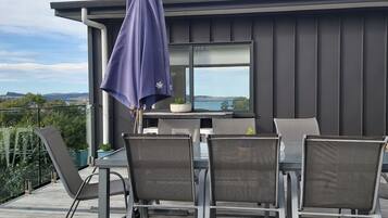 A modern outdoor dining area with a table and chairs, a potted plant, and a view of the landscape.