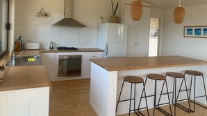 Una cocina moderna con una isla central, taburetes de bar, horno empotrado y refrigerador.