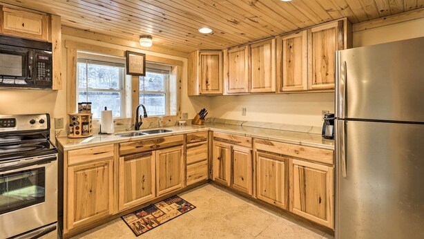 Una cocina con armarios de madera, electrodomésticos de acero inoxidable y una ventana con vistas a árboles.