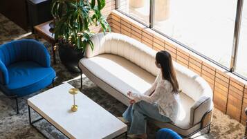 Un intérieur moderne avec un canapé, des fauteuils, une table basse et une grande plante en pot.