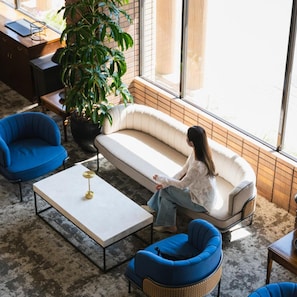A modern interior with a sofa, chairs, a coffee table, and a large potted plant. - Oarai Park Hotel (Oarai)