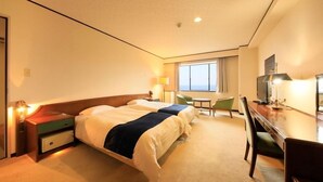 Ein Hotelzimmer mit zwei Betten, einem Schreibtisch, einem Stuhl, einem Fernseher und einem Fenster.