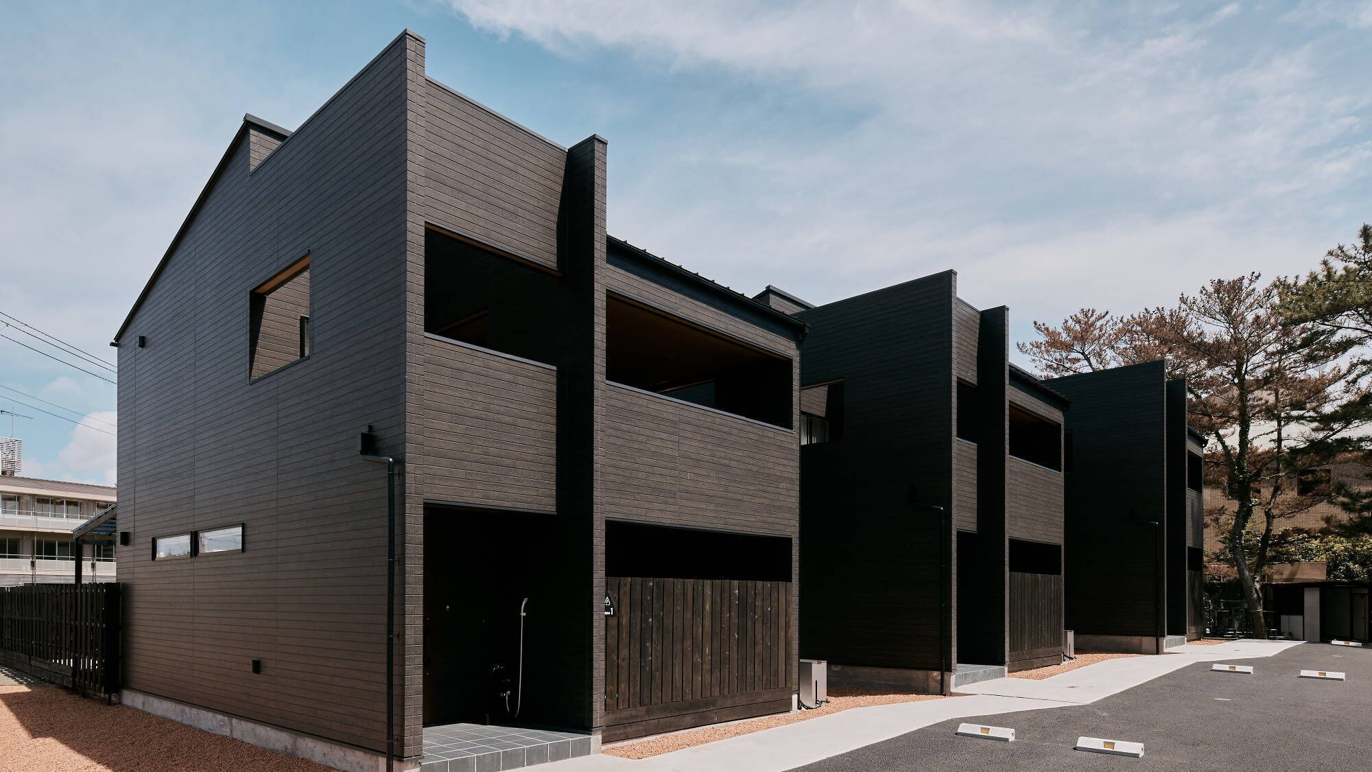 Un edificio moderno de dos pisos con techo plano, ventanas amplias y entrada de garage.