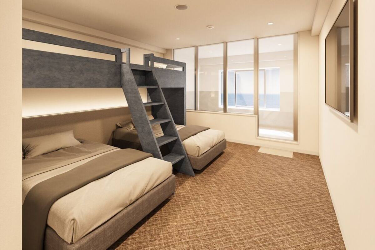 Een kamer met stapelbedden, een ladder en grote ramen.