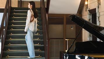 Une personne descendant un escalier, avec un piano en arrière-plan.