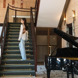 Eine Person geht eine Treppe hinunter, im Hintergrund steht ein Klavier.