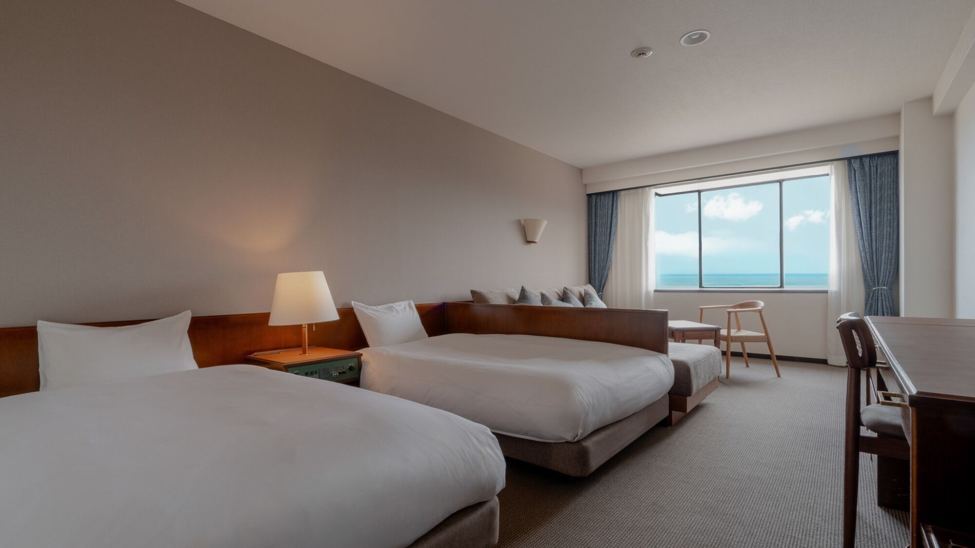 Habitación de hotel con dos camas, un escritorio y una silla.