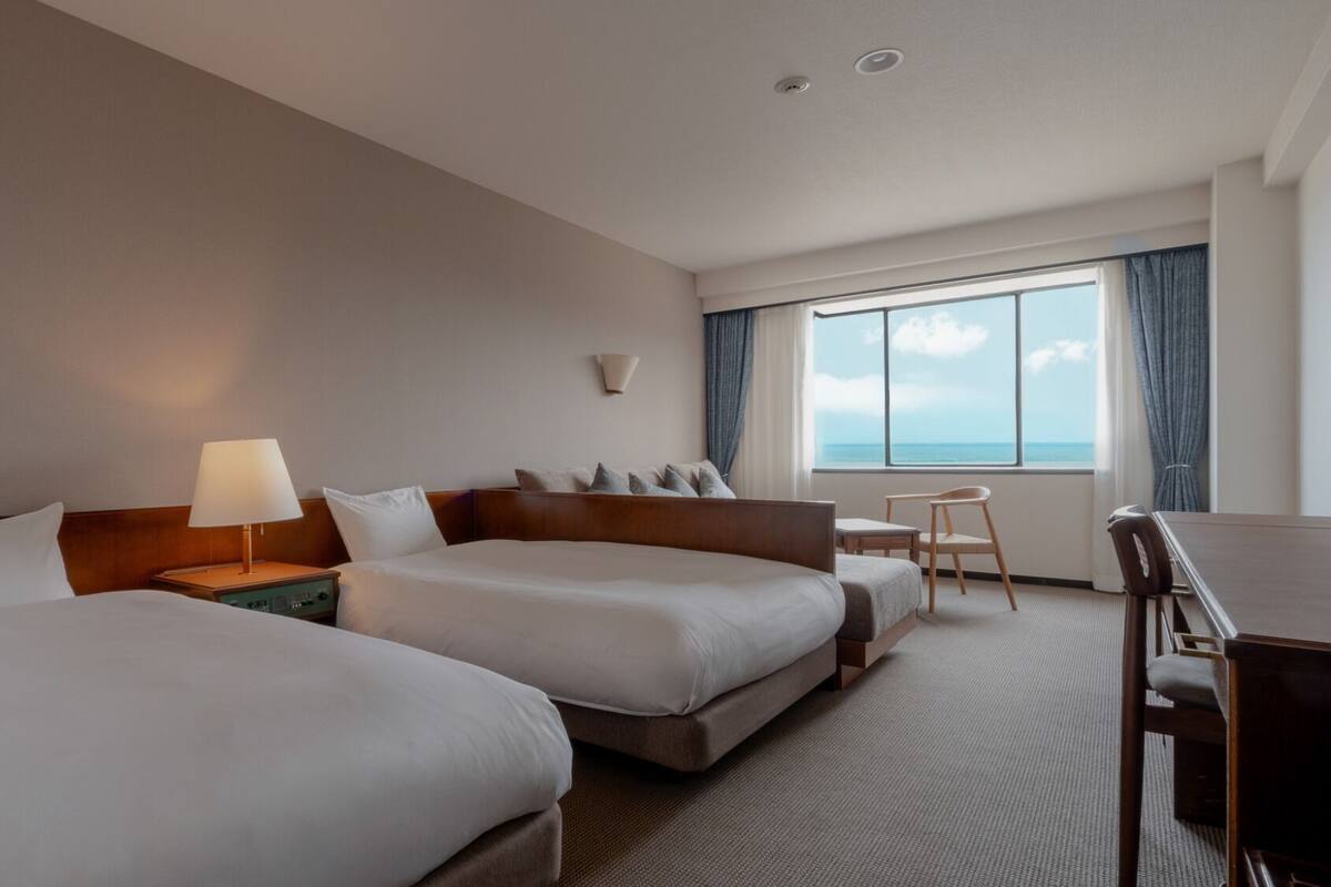 Een hotelkamer met twee bedden, een bureau en een stoel.