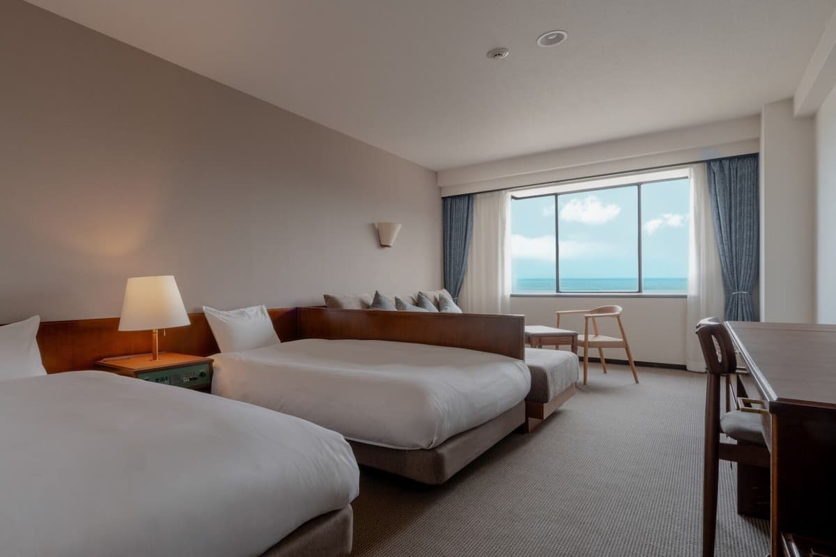 Habitación de hotel con dos camas, un escritorio y una silla.
