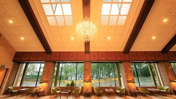A spacious lobby with a high ceiling, large windows, and a central chandelier.