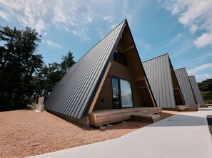 Een modern, driehoekig gebouw met een schuin dak, grote ramen en een houten terras.