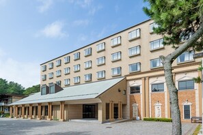 Un hôtel à plusieurs étages, doté d’un toit plat, de grandes fenêtres et d’une entrée centrale avec une allée couverte.