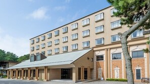 Ein mehrstöckiges Hotel mit schlichter Fassade, großen Fenstern und einem überdachten Eingangsbereich.