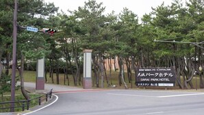 Eine Straße führt zum Oarai Park Hotel, im Hintergrund sind ein Ampelsignal und Bäume zu sehen.