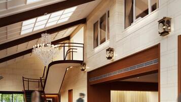 A spacious lobby with a grand chandelier, a staircase, and a reception desk.