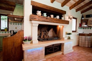 Cozy space with a stone fireplace, wooden beams, and a small window.
