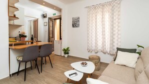 A modern living room with a sofa, a small coffee table, and a dining area with chairs and a table. - Apartment Family Tokić  (Dubrovnik)