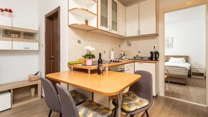 A compact kitchen with a dining area, wooden cabinets, and a small seating space. - Apartment Family Tokić  (Dubrovnik)